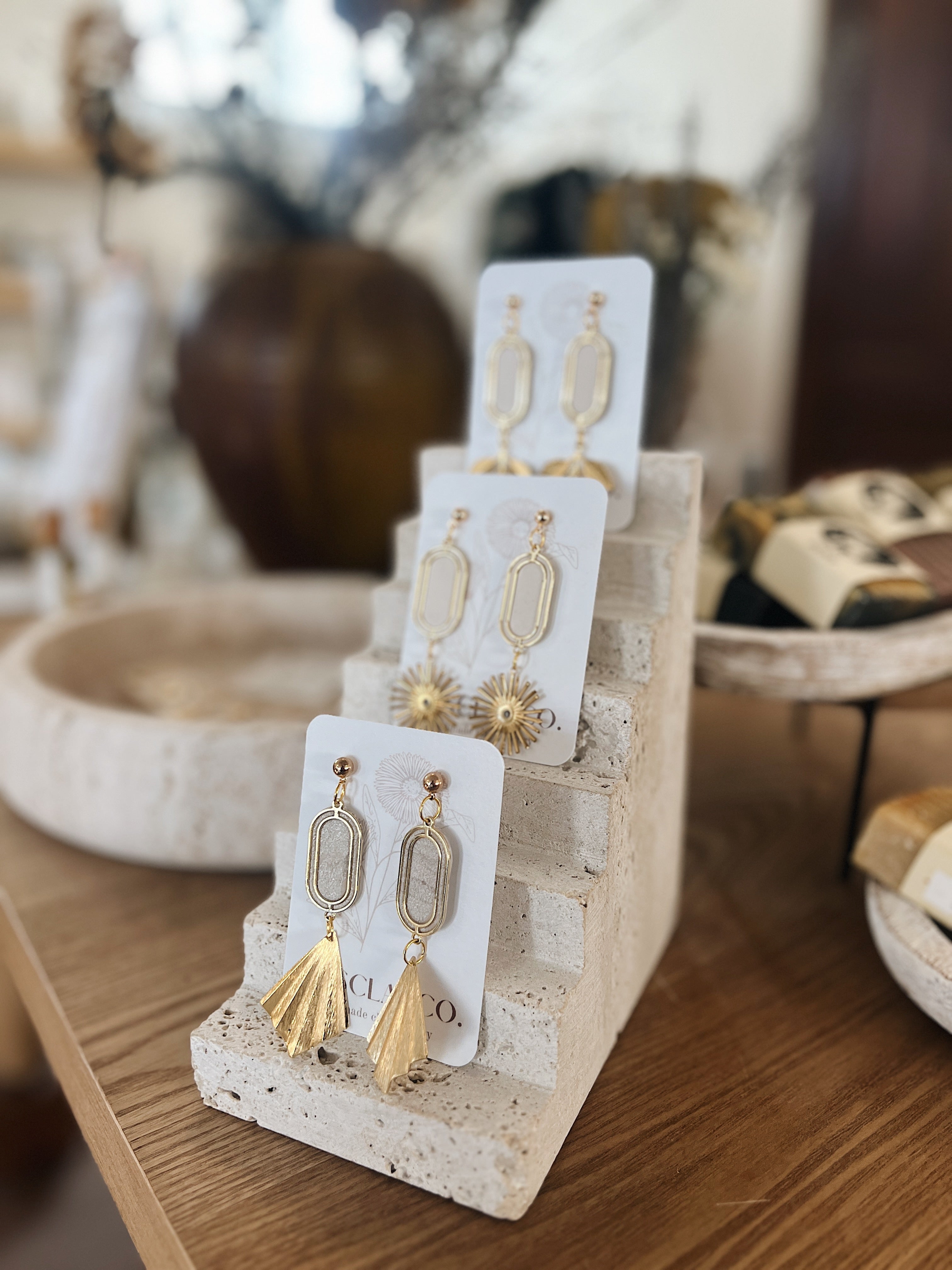 Three statement earrings stacked on display on wooden table