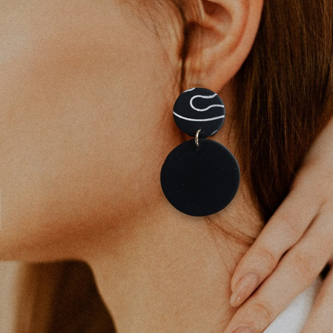 Woman profile modeling large black statement earring