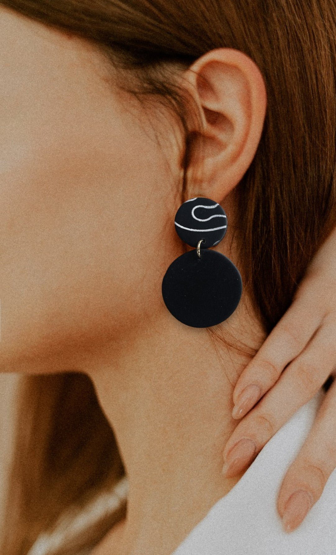 Woman profile modeling large black statement earring